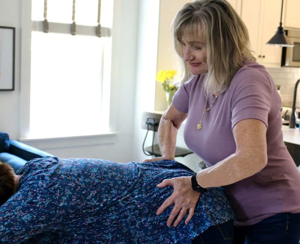 A woman getting a massage from a woman in a blue bed.