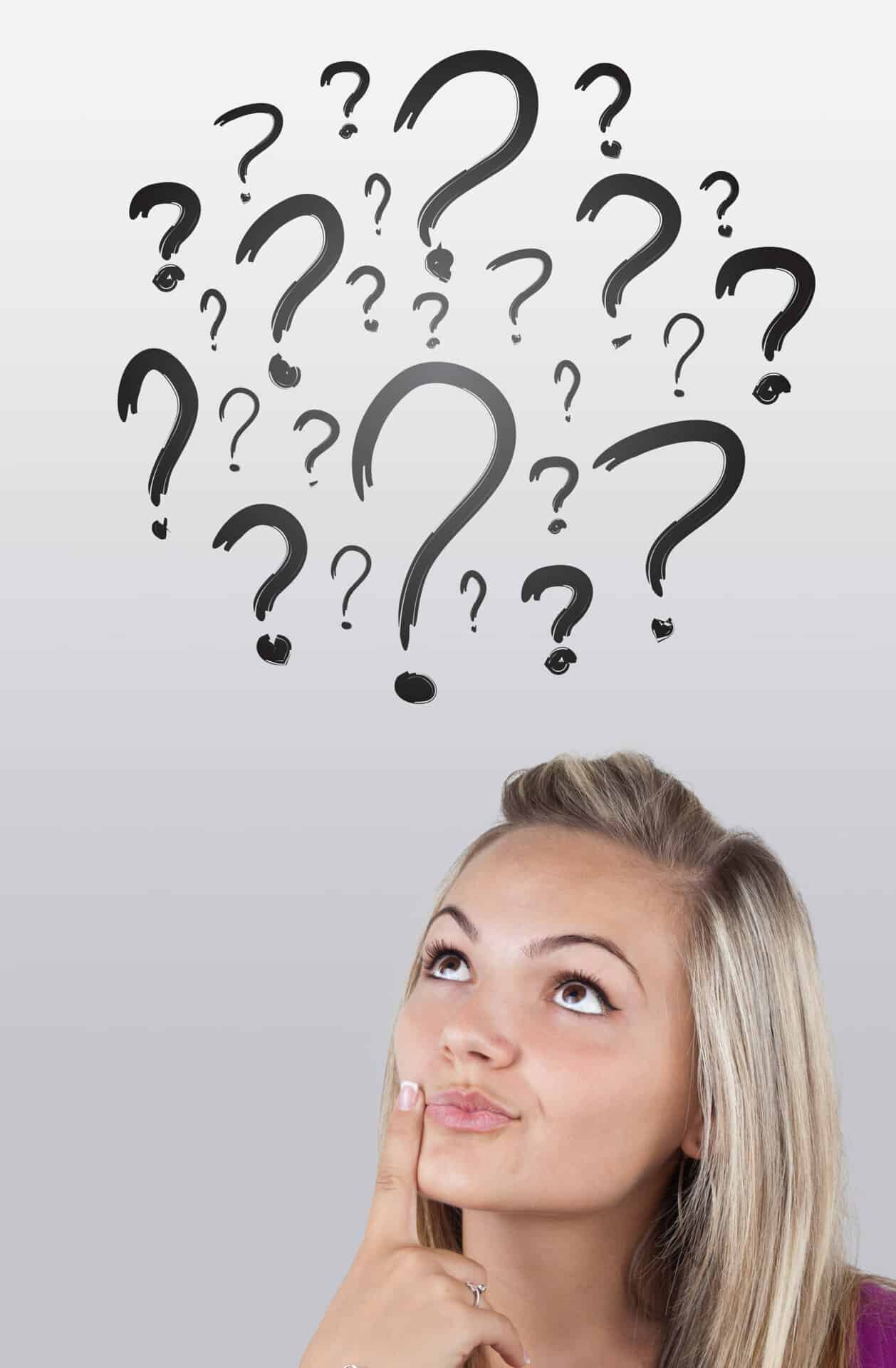 A woman looking up at question marks above her head.