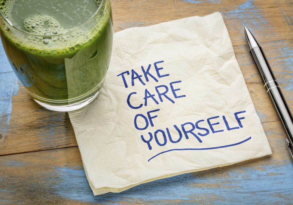 take care of yourself - inspirational handwriting on a napkin with a glass of green juice