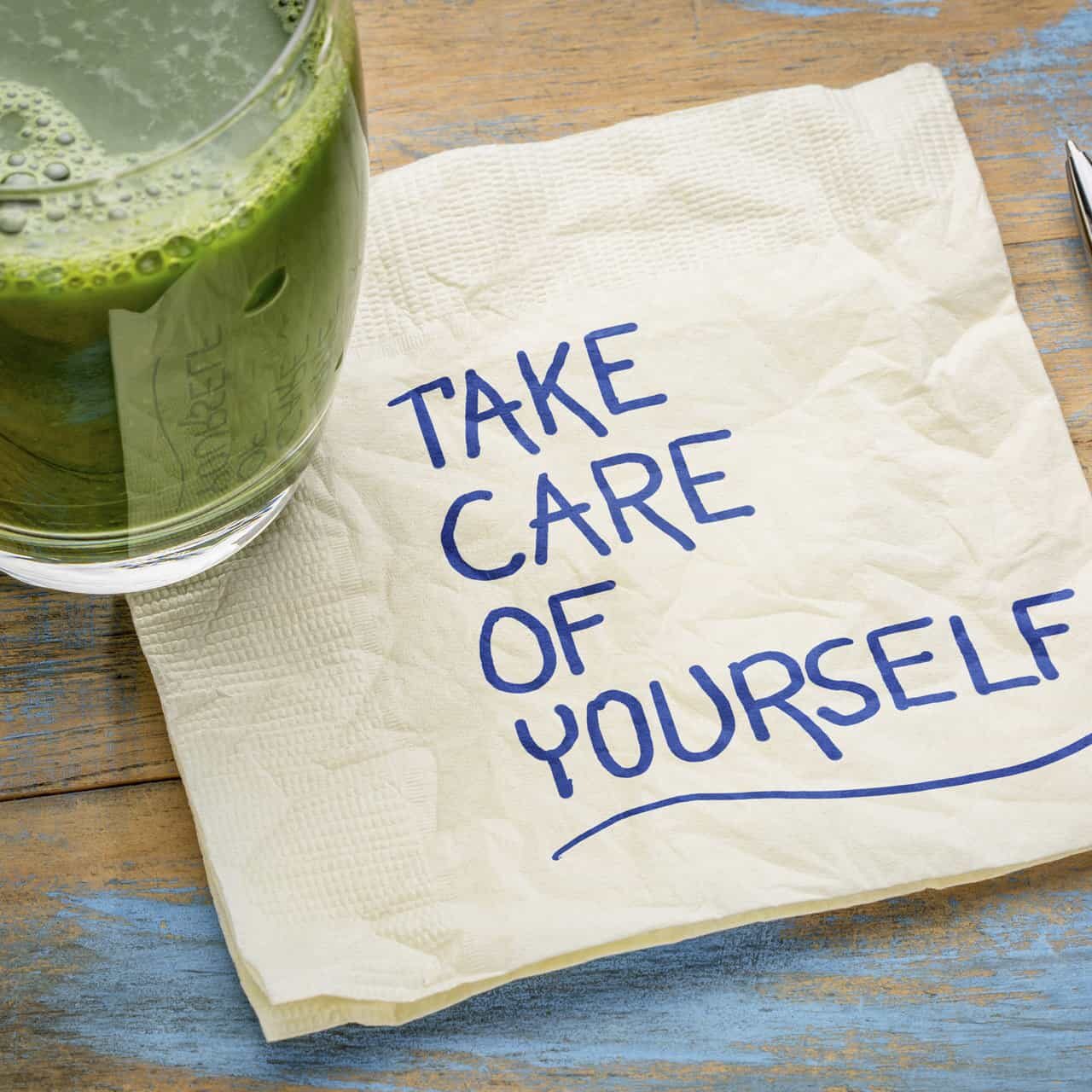 A napkin with the words take care of yourself on it next to a cup of.